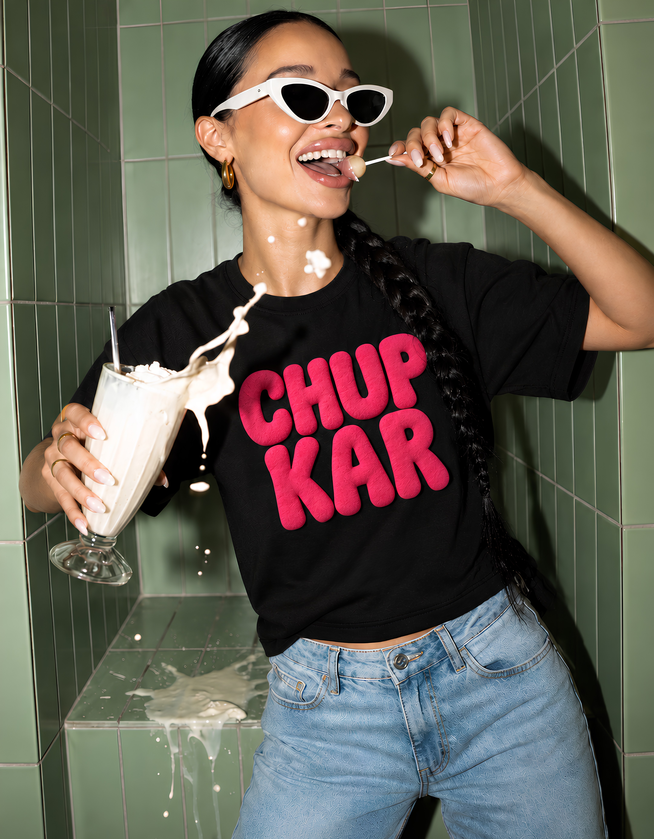 Model in the black Chup Kar tee holding a milkshake against a green tiled wall